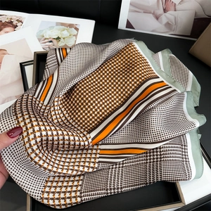 Close-up of houndstooth silk scarf with elegant brown and orange patterns on a tray