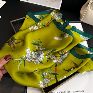 Detail of silk scarf showing peach blossom and butterfly patterns with deep green rolled edges