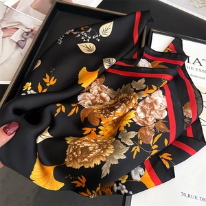 Close-up of silk scarf fabric showing floral ginkgo patterns and red striped edges