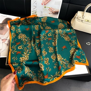 Macro detail of the green silk scarf featuring bird and yellow floral prints with orange border
