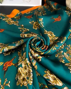 Detailed view of dark green silk scarf with birds pattern and orange edge