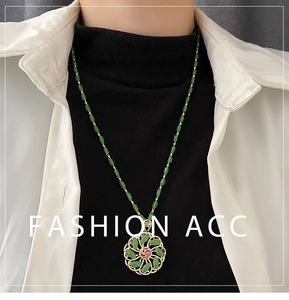 Close-up of a rotating green flower pendant necklace on a model with golden chain details