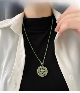 Close-up of a floral pendant necklace with green tubular beads on a model's neck