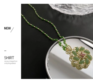 Macro shot of rotating green floral pendant with gold-plated alloy and beaded chain