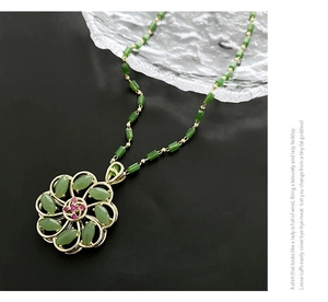 Detail of green petal pendant necklace with purple gems and gold beaded chain link