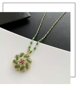 Detail of a rotating lucky flower pendant with green jade petals and red gemstone core