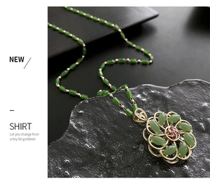 Macro detail of rotating green flower pendant necklace with elegant gold beaded chain