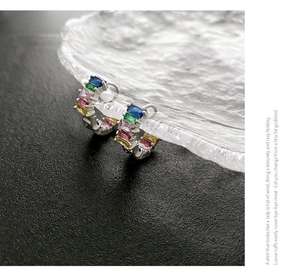 Macro shot of silver hoops set with colorful rectangular-cut rainbow gemstones
