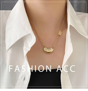 Macro detail of gold bean necklace with LUCK rhinestone engraving on a fashion model