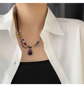 Detail of trendy mixed beaded necklace with black bear pendant and metallic spike