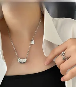 Detailed view of model wearing a bean pendant necklace and silver leaf ring set
