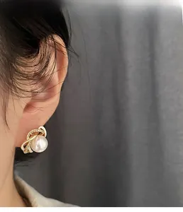 Close-up of elegant flower pearl earrings with crystals on woman's earlobe