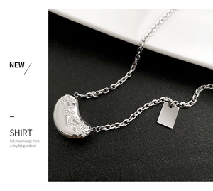 Detail of silver crescent pendant with LUCK zircon inlay on a delicate link chain