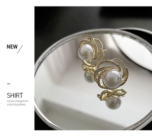 Close-up of golden spiral flower pearl earrings with crystals on a mirror