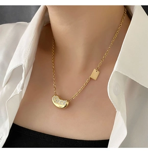 Close-up of golden bean necklace with Lucky engraving and side rectangle charm detail