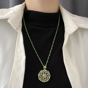 Elegant rotating green flower pendant necklace with jade-style beads and gold accents