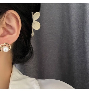 Close-up of golden spiral pearl earrings with shimmering micro-pave crystals on model