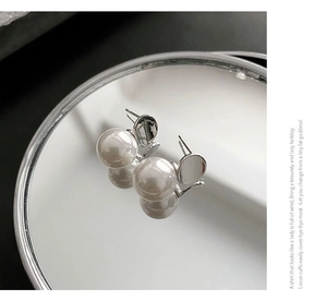 Close-up of minimalist faux pearl stud earrings with elegant silver metal base
