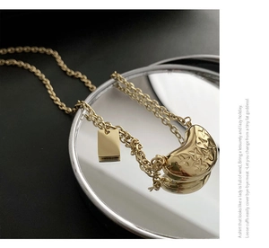 Detail of gold bean pendant with cross star texture and rectangular metal brand tag