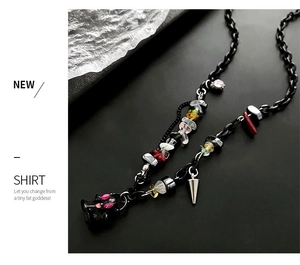 Detail of dark metal chain necklace featuring colorful crushed stones and a cat pendant