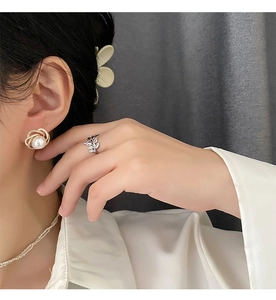 Detail shot of French pearl earrings and leaf ring styled on a female model