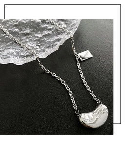 Macro detail of silver tone Luck pendant and rectangular tag on minimalist chain necklace