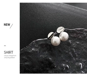 Close-up of elegant silver pearl earrings on a glass prop with artistic shadows