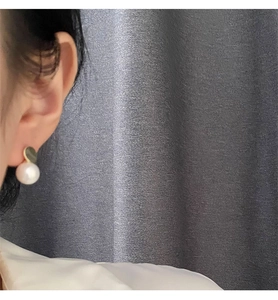 Close-up of elegant gold disc earring with a hanging white pearl on the earlobe