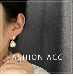 Close-up of elegant pearl drop earrings with crystal studs and a floral cluster ring