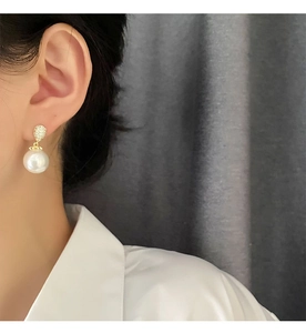 Detail of elegant pearl earrings featuring micro-set zircon drops worn on a model