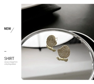 Macro detail of gold-plated butterfly stud earrings with micro-pave crystals on a mirror
