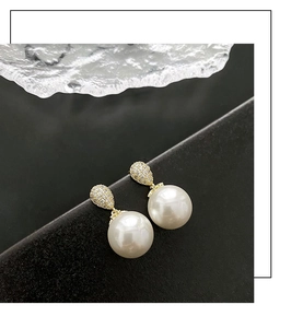 Close-up of elegant pearl drop earrings with sparkling zircon-set pear-shaped studs