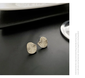 Macro shot of irregular wave-shaped gold earrings with sparkling pave-set zircons