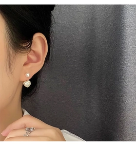 Detail of elegant pearl earring with heart diamond pendant and silver flower ring
