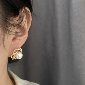 French style floral pearl earrings with gold accents worn by a model on a grey background