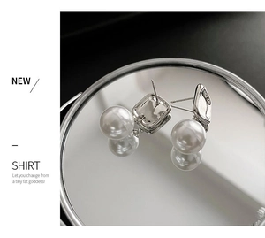 Detail of square pearl earrings on a mirror surface with elegant light reflections