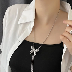 Elegante collana con ciondolo a farfalla argentata e anello coordinato su modella minimalista