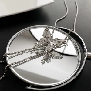 Collana farfalla argento con trama lavica su superficie riflettente a specchio