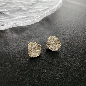 Sparkling pebble-shaped gold earrings set with micro-pave crystals on glass tray