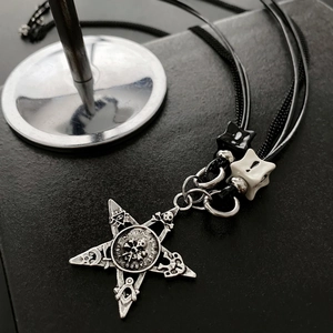Macro shot of silver gothic star pendant with engraved occult symbols on black rope