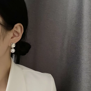 Elegant geometric square metal earrings with round white pearls on a female model