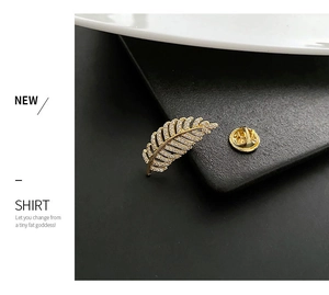 Detailed macro of a gold feather brooch with micro-pave zircons and butterfly clasp back