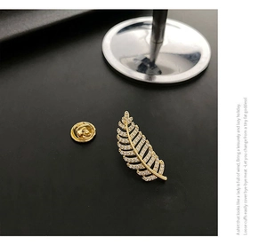 Detailed close-up of leaf brooch featuring micro-set cubic zirconia and gold finish