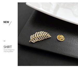 Detail of a gold feather brooch with micro-paved cubic zirconia and butterfly clutch back