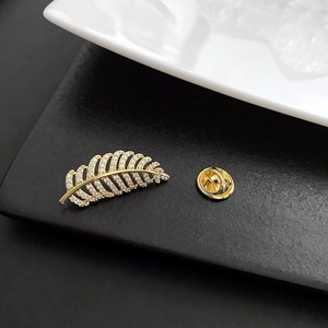Exquisite gold-plated leaf brooch with micro-pave zircons on a dark textured background