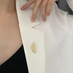 Exquisite golden feather brooch with micro-pave zircons pinned on white blazer lapel