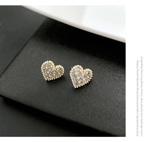 Detailed close-up of heart-shaped gold studs with pavé zircons and micro pearl edges