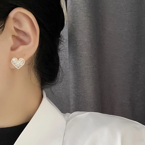 Elegant heart-shaped pearl and crystal stud earrings in gold plating worn by model