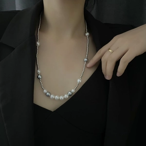 Detail of trendy beaded necklace with white pearls and silver metal beads on a black suit
