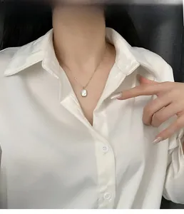 Close-up of elegant silver necklace with rectangular white shell pendant worn by a model